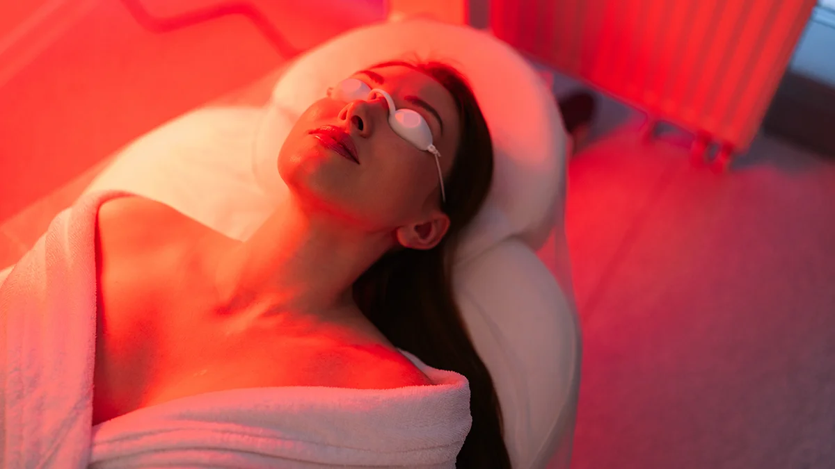 A woman geting red light therapy with eye protection in a clinic due to very strong red led light